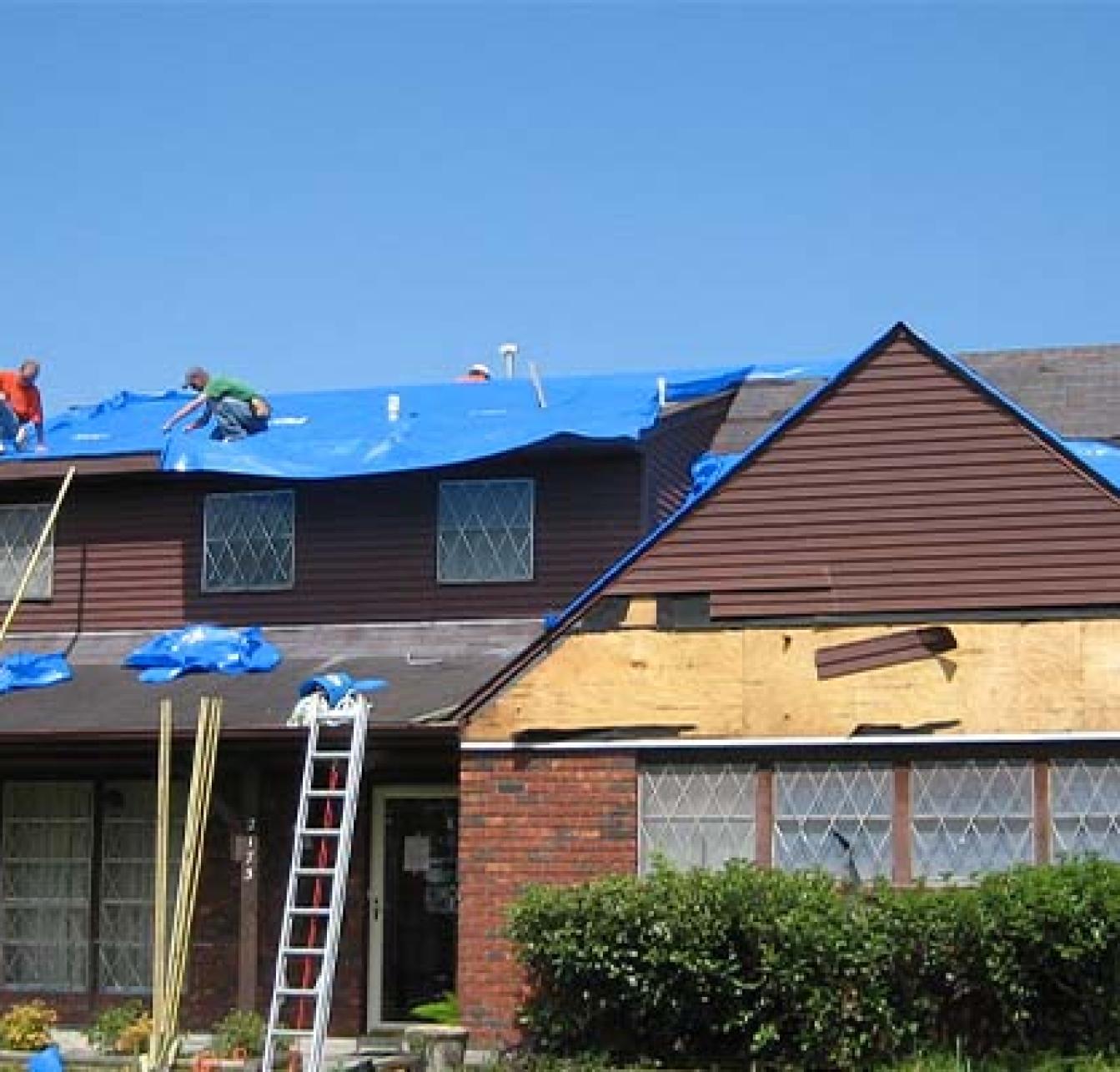 images of roofers laying tarp on a roof